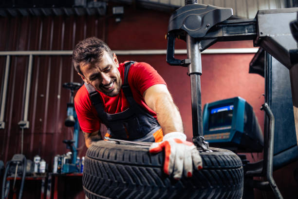 Experienced worker changing tire in car repair shop.
