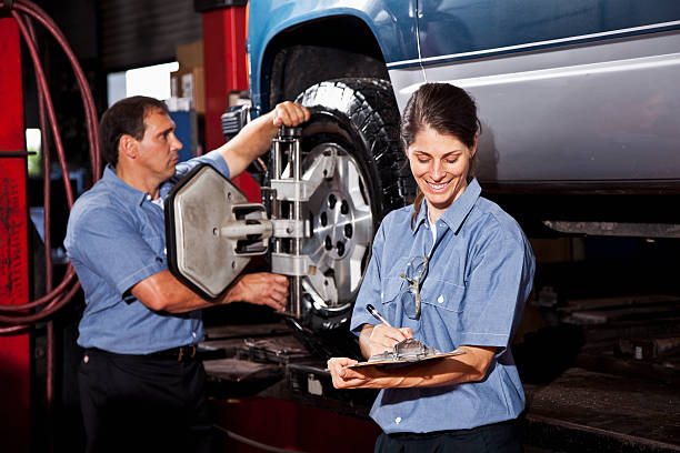 Car mechanics performing wheel alignment.