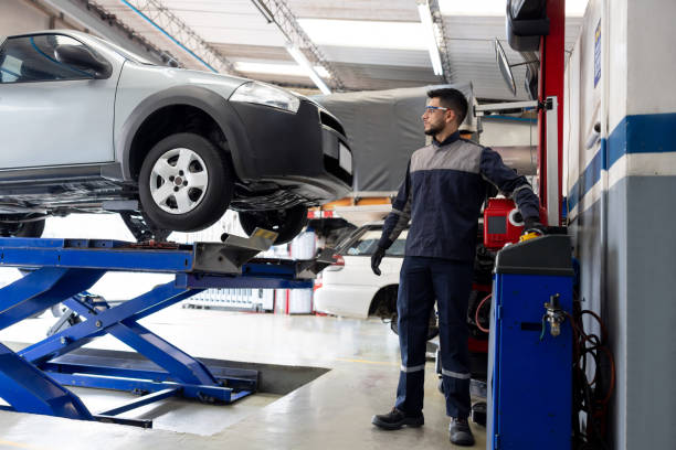 Latin American mechanic fixing a car at an auto repair shop and lifting it with a car jack
