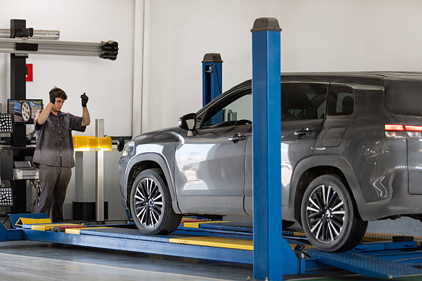 Male Mechanic directing driver to drive car onto tire alignment and balancing station mechanic