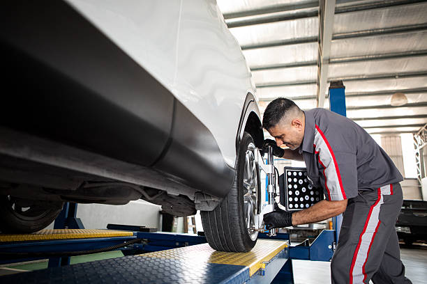 Mechanic works on wheel alignment and balancing in a mechanic shop